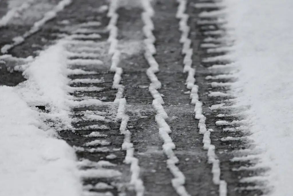 Reifenspuren im Schnee auf einer vereisten Straße.
